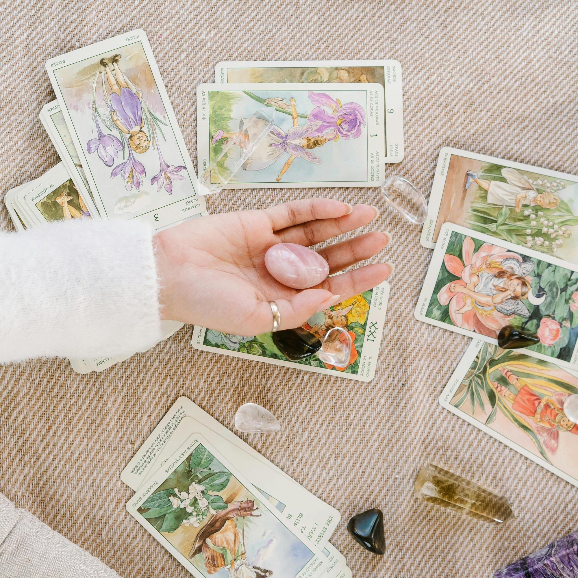 Hand met rozenkwarts en tarotkaarten tijdens intuïtieve legging – sfeerbeeld van de live tarot jaarlegging 2026 bij Marga Jacobs