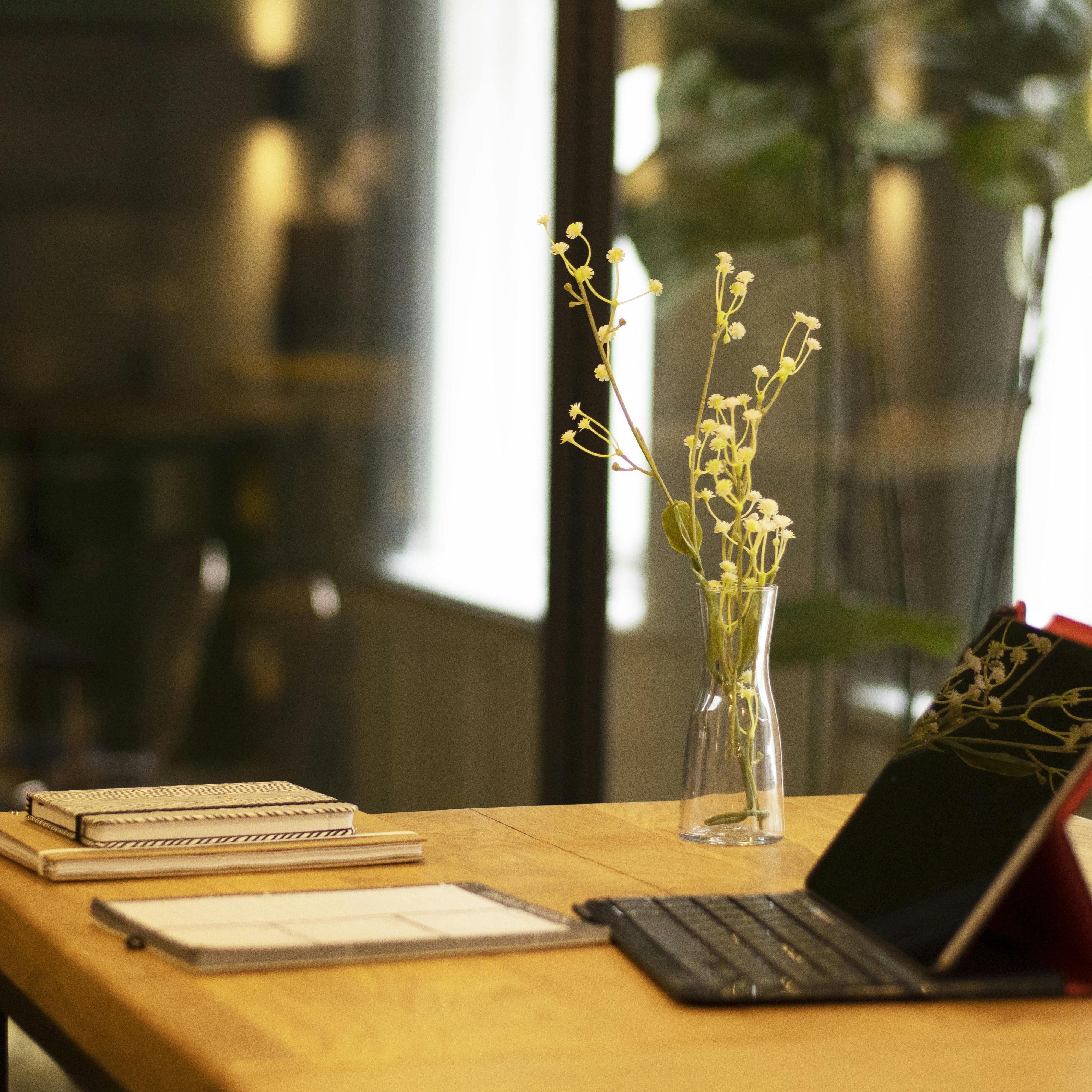 Laptop met toetsenbord en bloemenvaas op een rustige werkplek, ideaal voor online coaching via Google Meet.